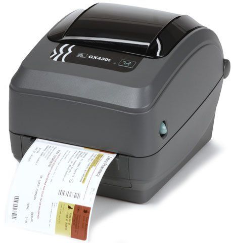 A Zebra GX430t thermal transfer barcode label printer with a label coming out of the slot, predominantly gray in color.